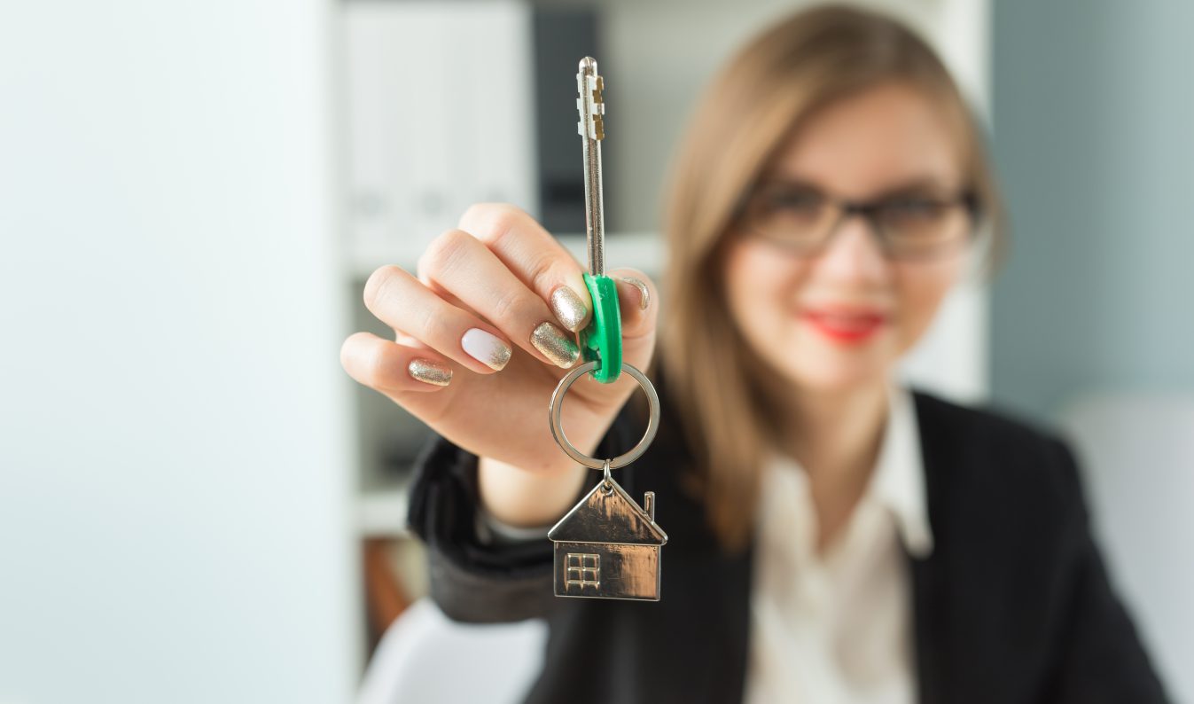 New home and real estate concept - Close up of happy realtor woman with red lips giving you keys from new apartment